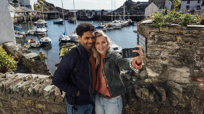 A couple taking a selfie using a smart phone while on holiday in Polperro, Cornwall.