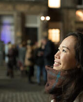 Una mujer asiática mira hacia arriba y observa el espectáculo de luces en George Street, Edimburgo
