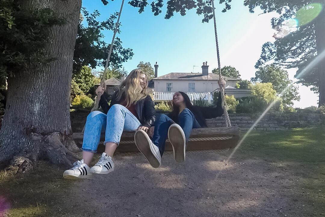 Two women on a swing in a hotel garden