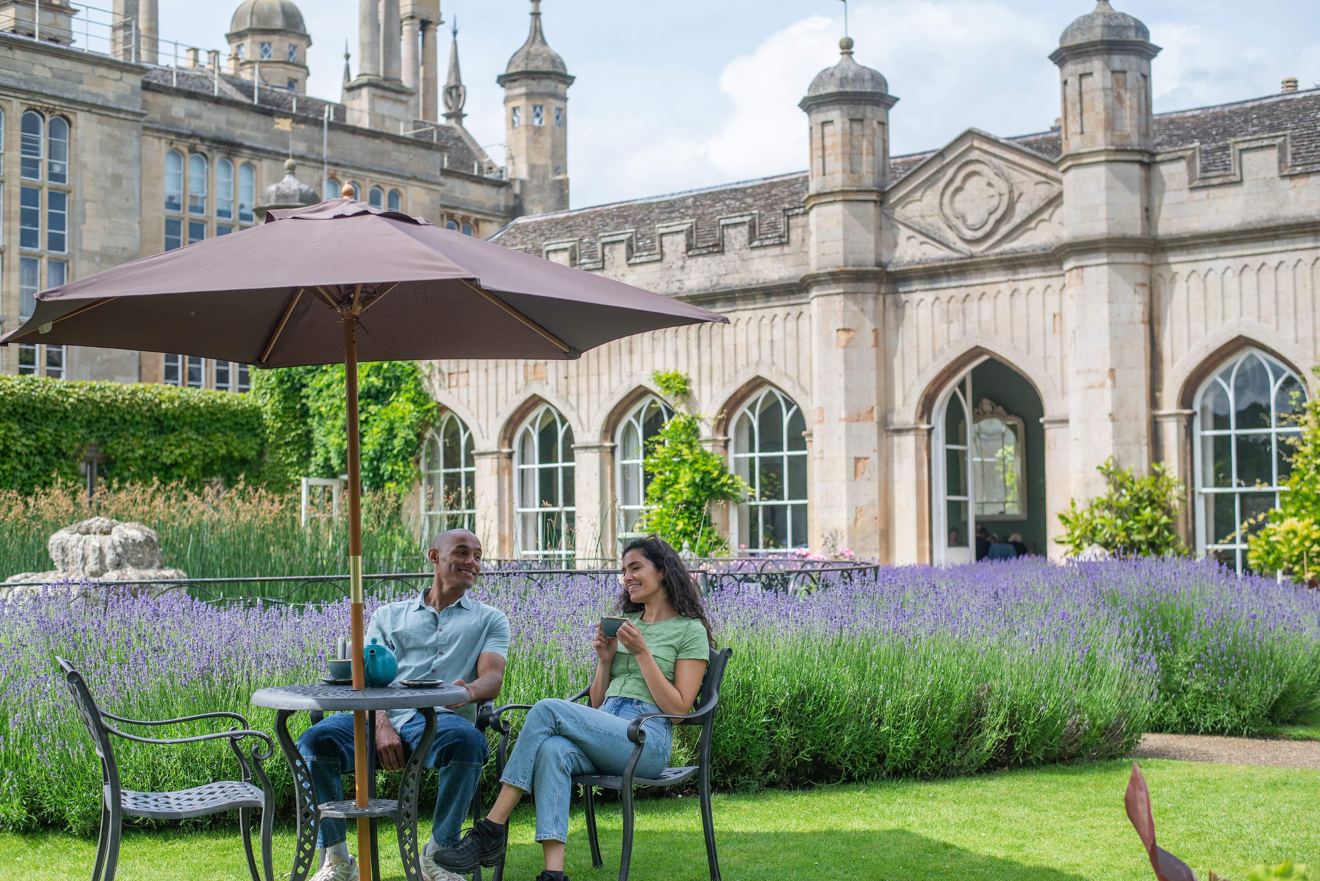 A man and a woman drink tea together in the gardens of a heritage house