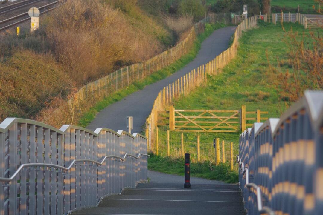 View down a bridge over a train line with the estuary in the distance