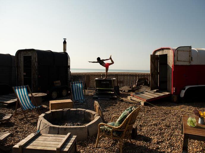 Woman holds a yoga pose standing on the edge of small plunge pool on the beach