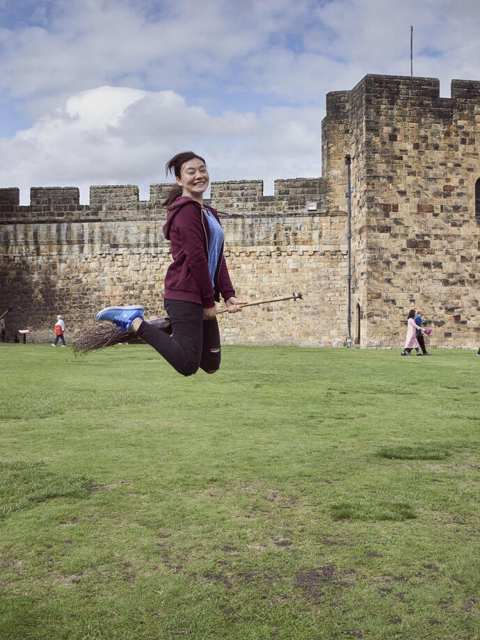 Femme sur un balai devant un château