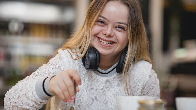 Young female with Down's Syndrome sat at a table laughing