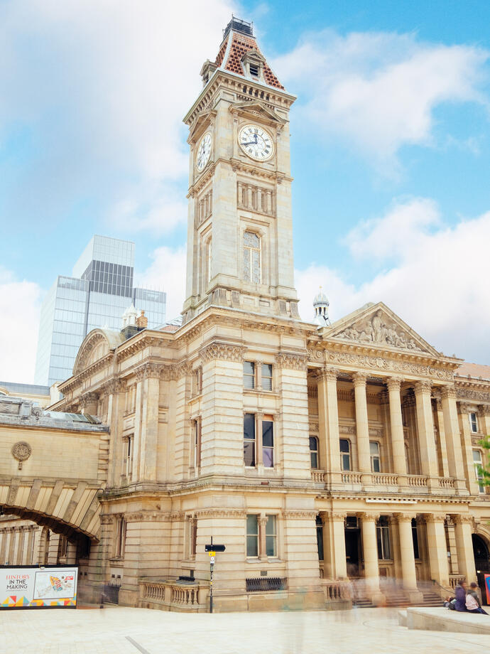 Large building with pillars and a clock tower on a sunny day