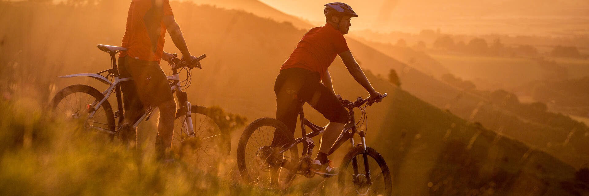 Two men on mountain bikes cycling at Devil's Dyke. Sunrise