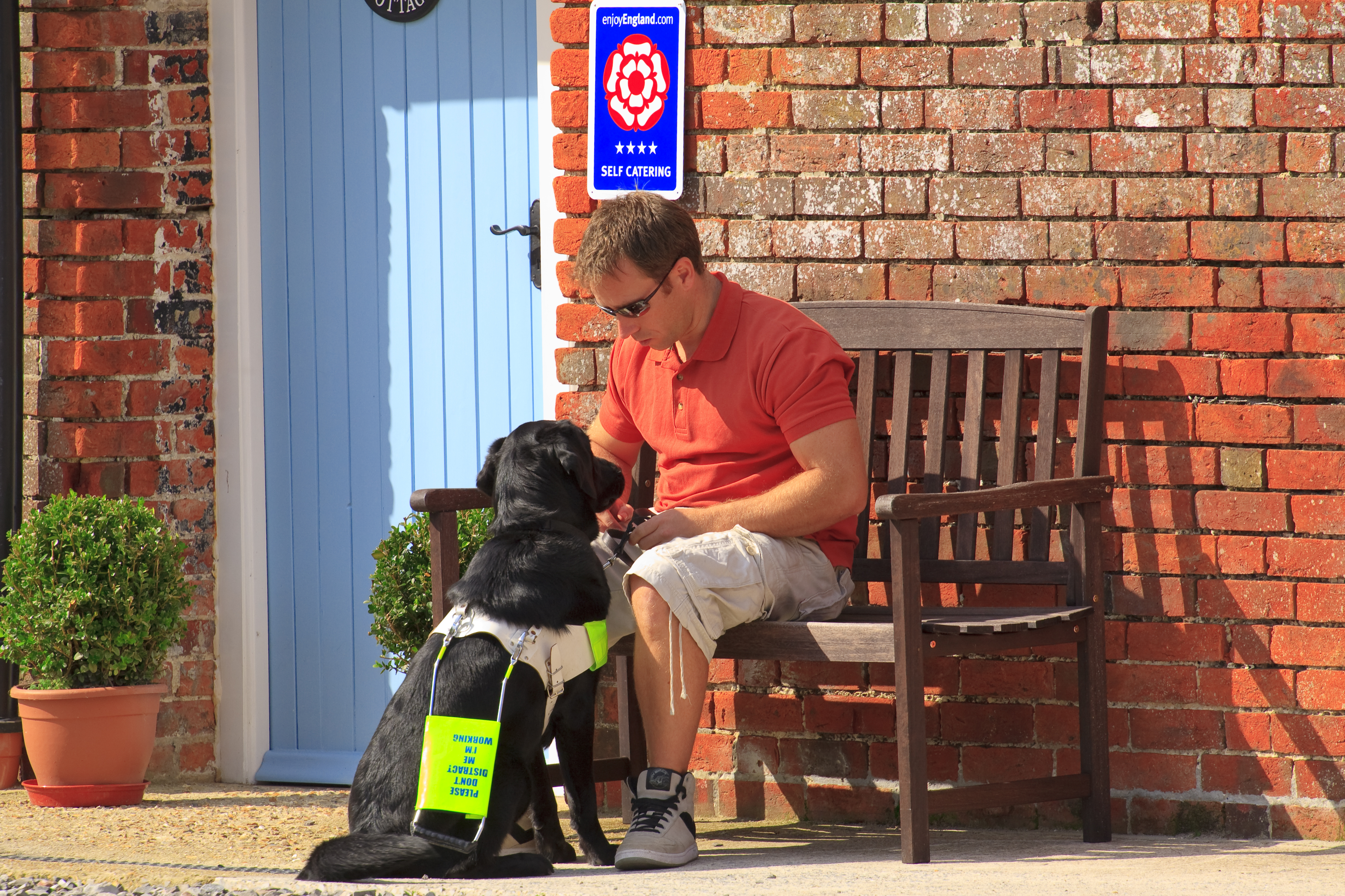 A man sat on a bench with his assistance dog