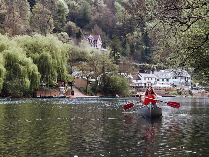 A woman in a canoe with hills and buildings behind