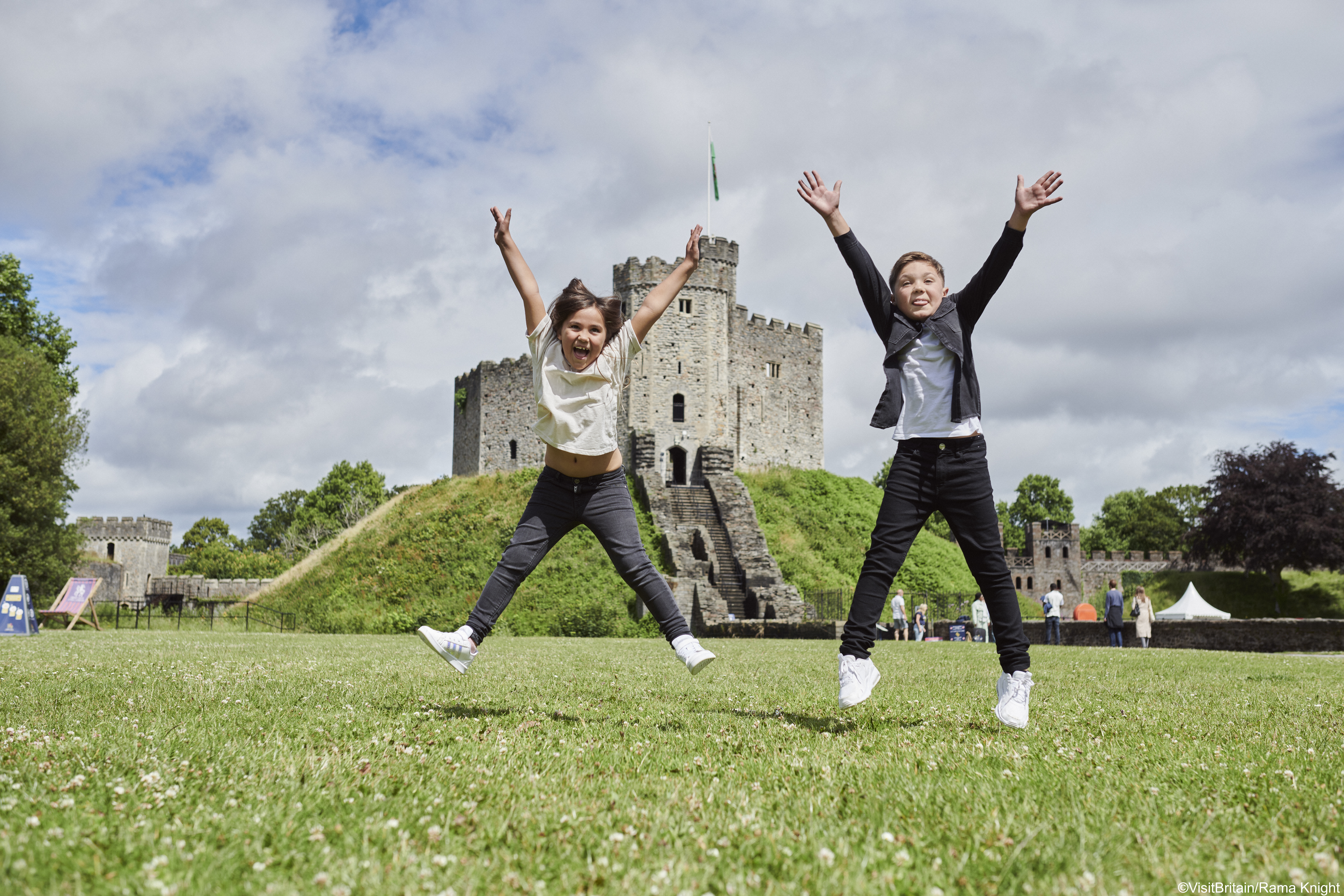 Zwei Kinder springen vor einem Schloss.