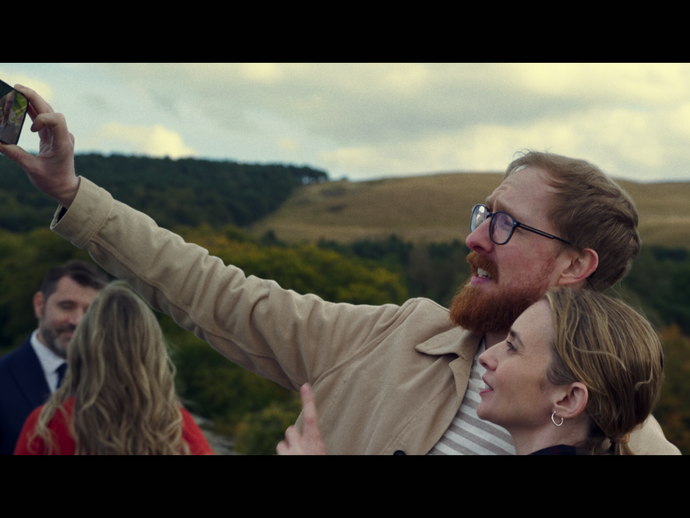 Un uomo scatta un selfie con una donna nel parco di una dimora storica