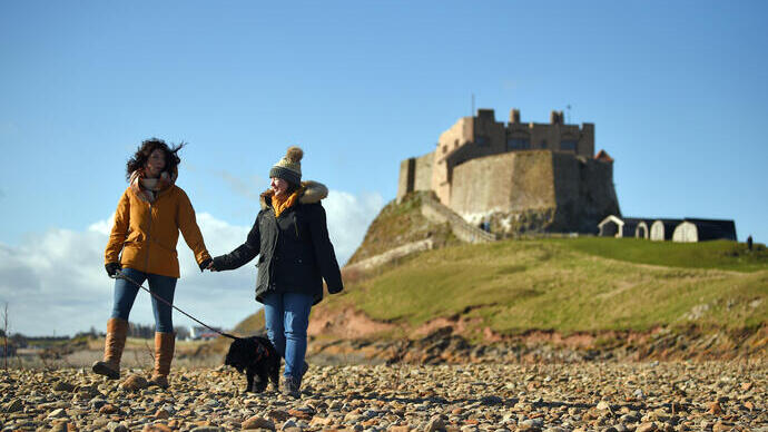 Besucher, die mit ihrem Hund im Lindisfarne Castle in Northumberland spazieren gehen