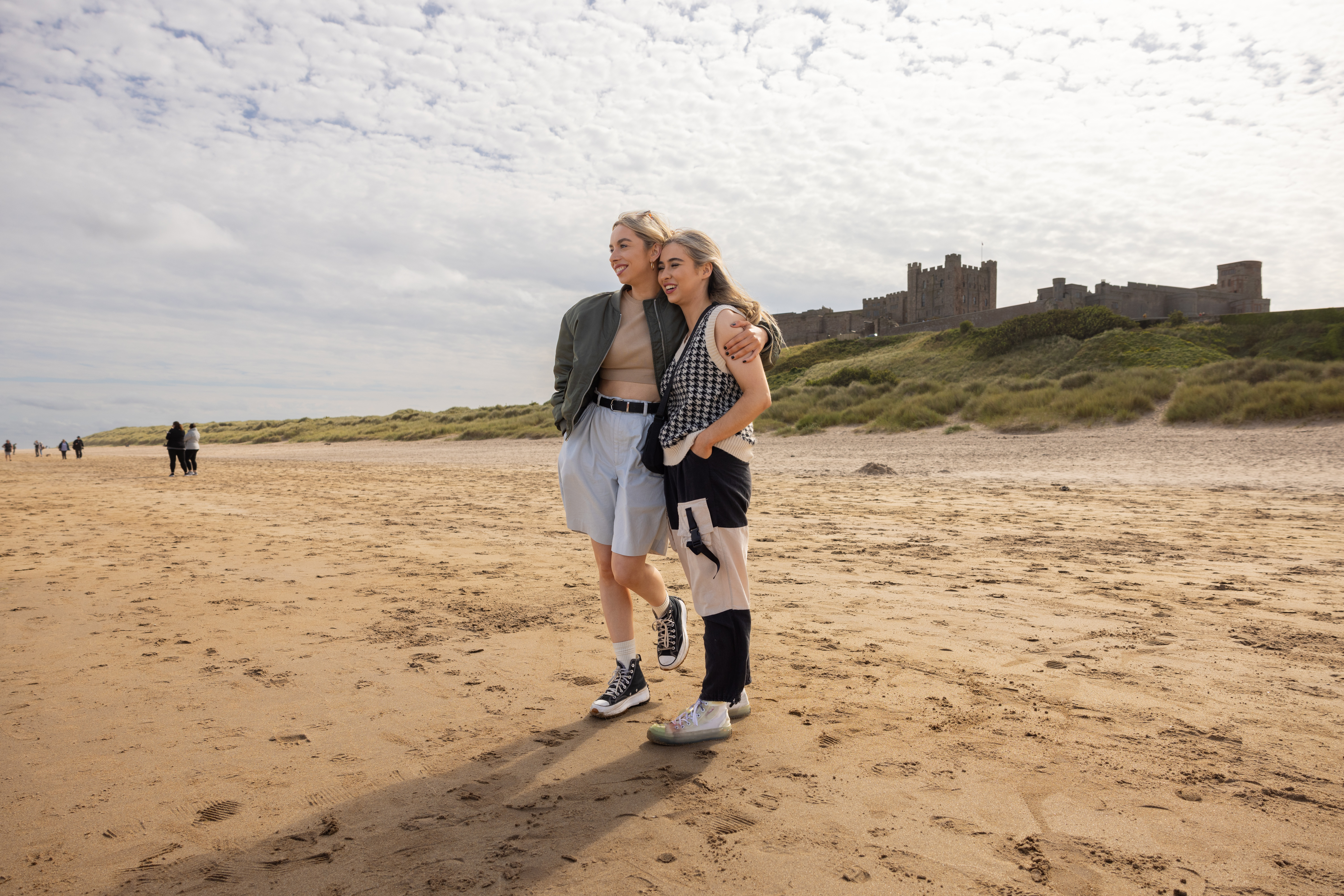 Zwei Frauen umarmen sich am Strand in der Nähe einer Burg