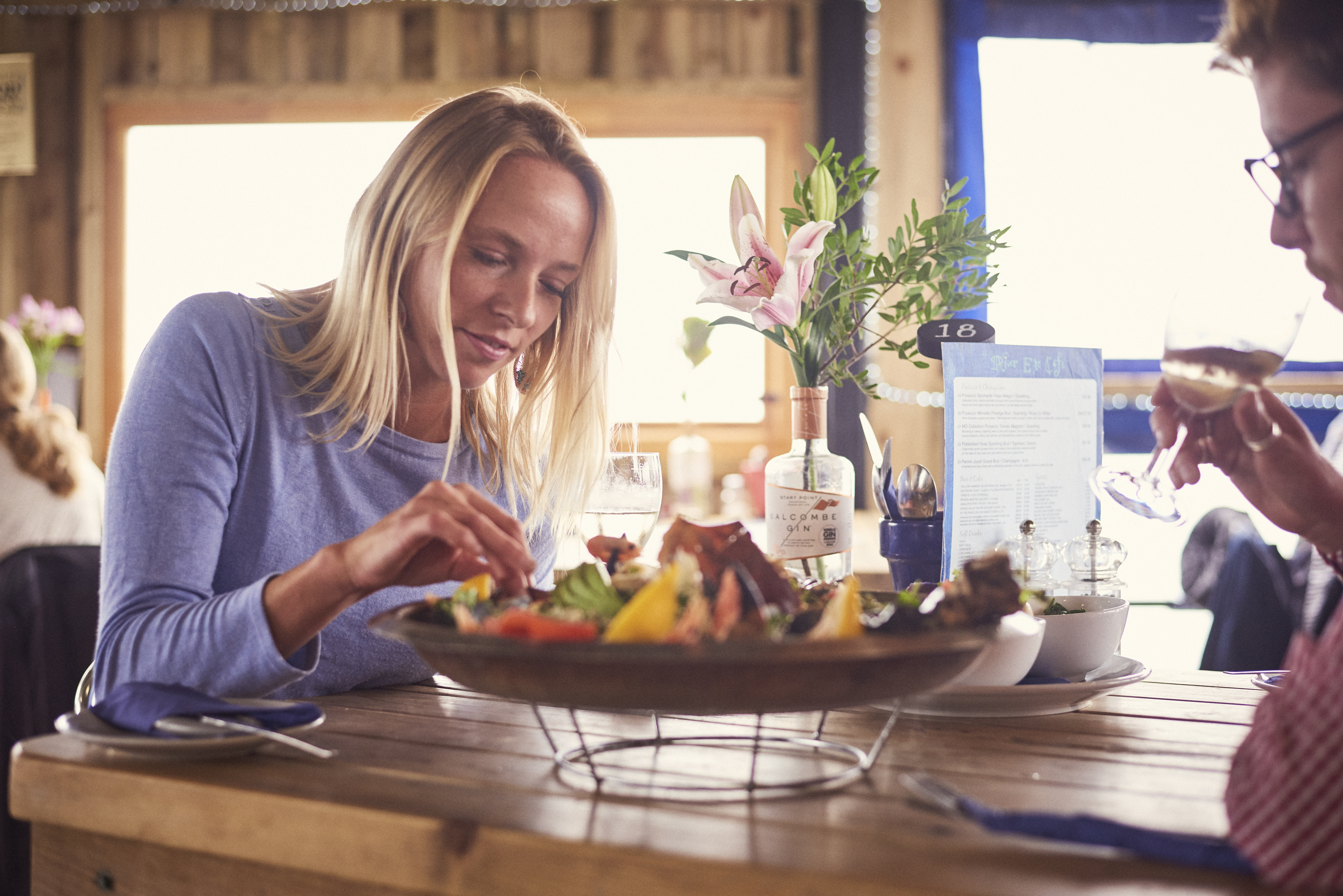 Blond woman and man sitting at table, eating seafood platter