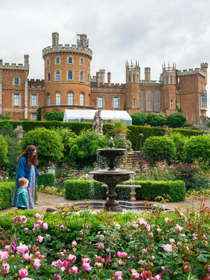 A woman and a child walk in the gardens of a castle