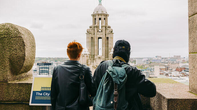 Man and woman standing atop historic building overlooking cityscape