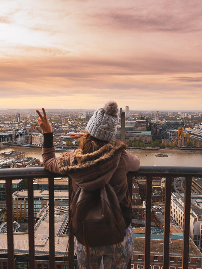 Woman on a balcony at the top of a high building looking over a city