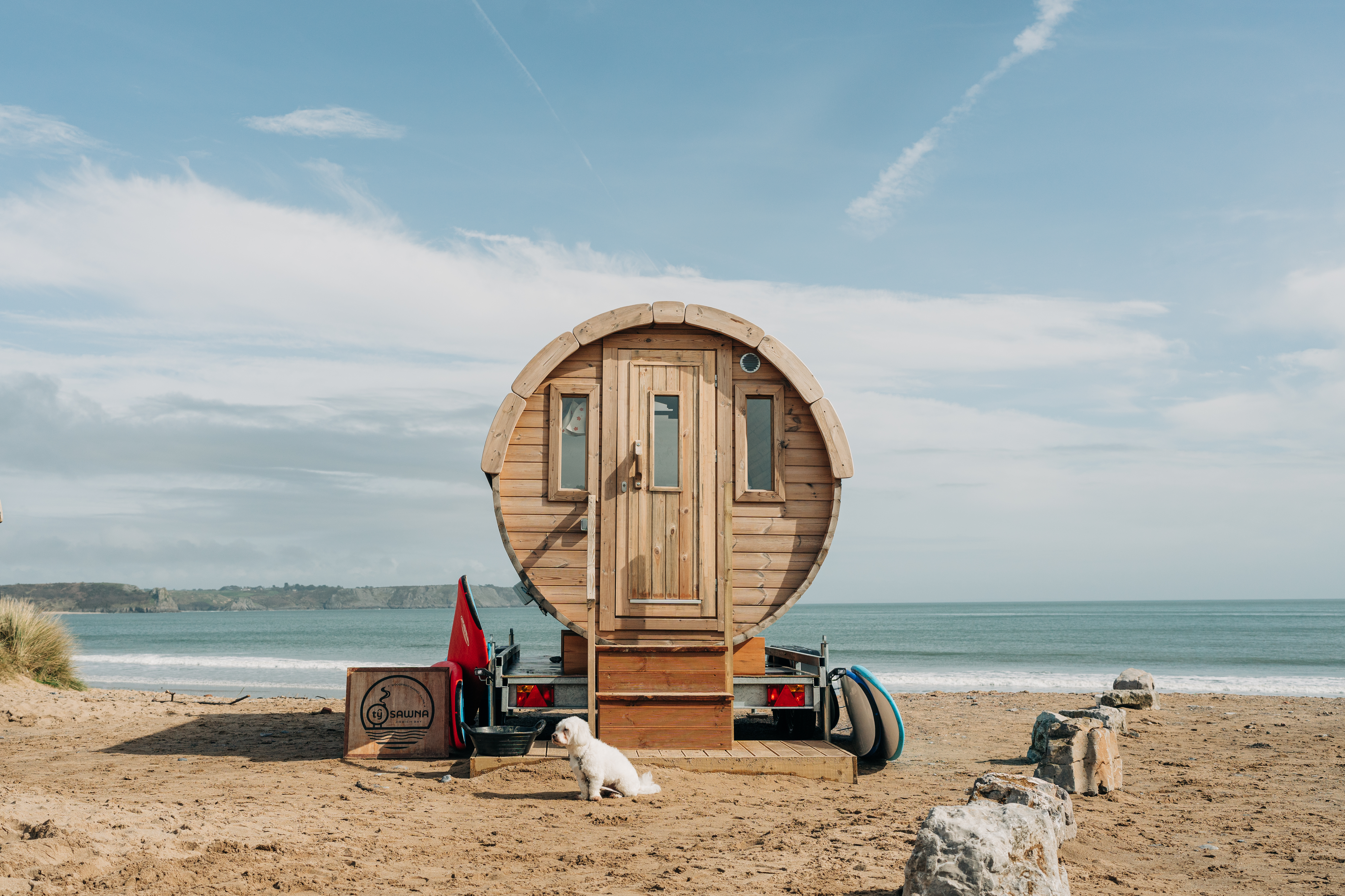 Una sauna de playa construida expresamente para tal fin, aparcada en la arena junto al borde del océano.