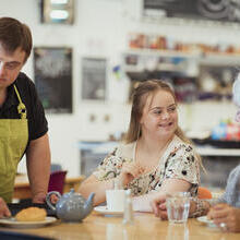A person with Down's Syndrome serving customers in the cafe