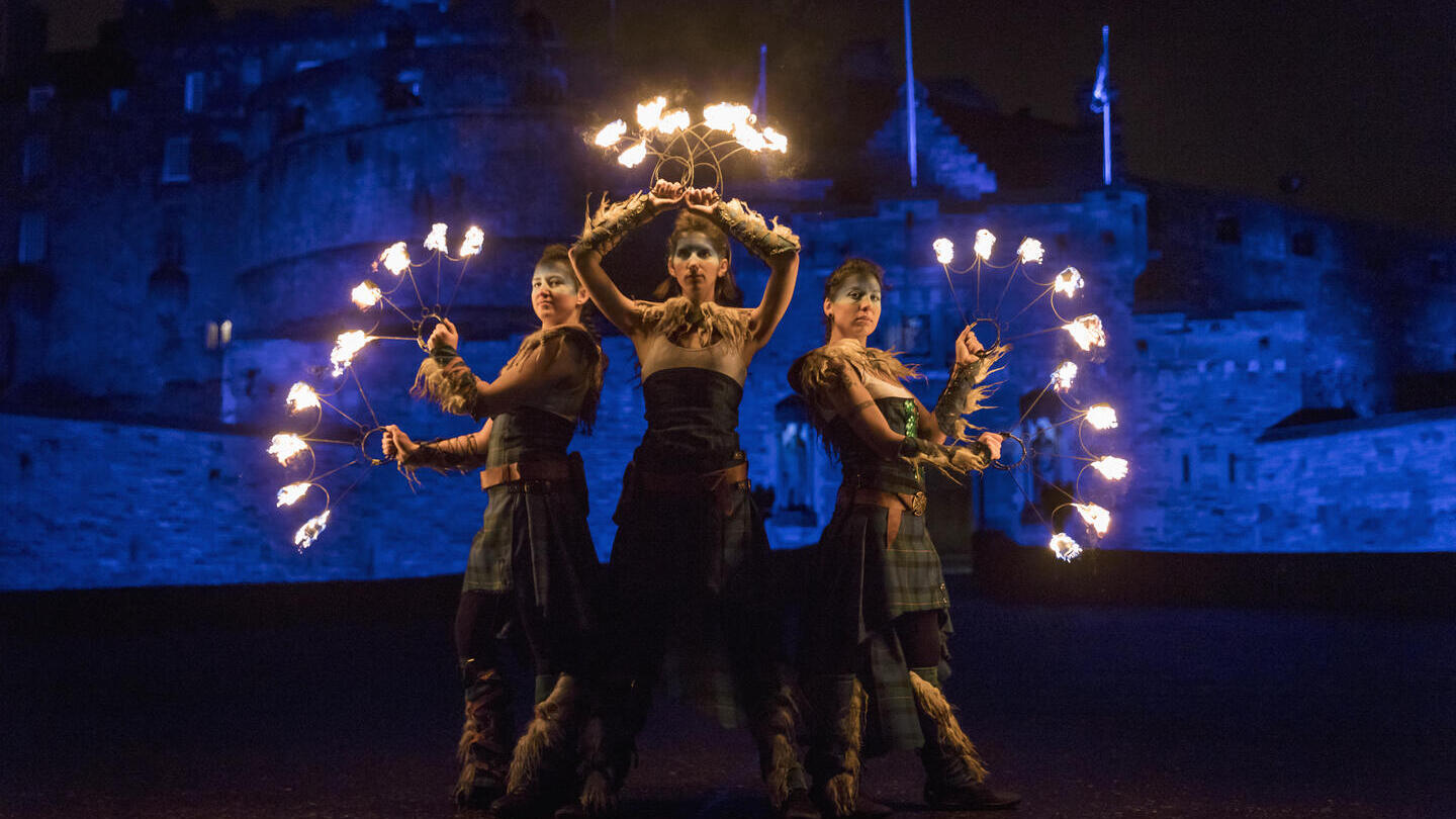 A procession of dancers with fire torches near North Bridge outside Edinburgh Castle