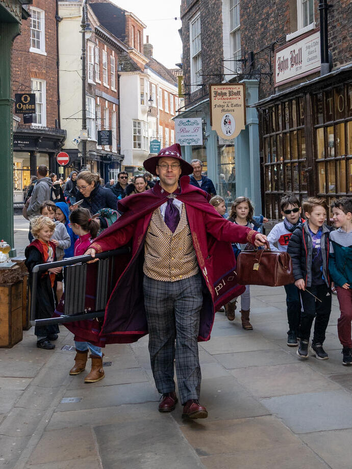 A costumed guide in a wizard outfit walking through the street, part of The Wizard Walk of York, North Yorkshire