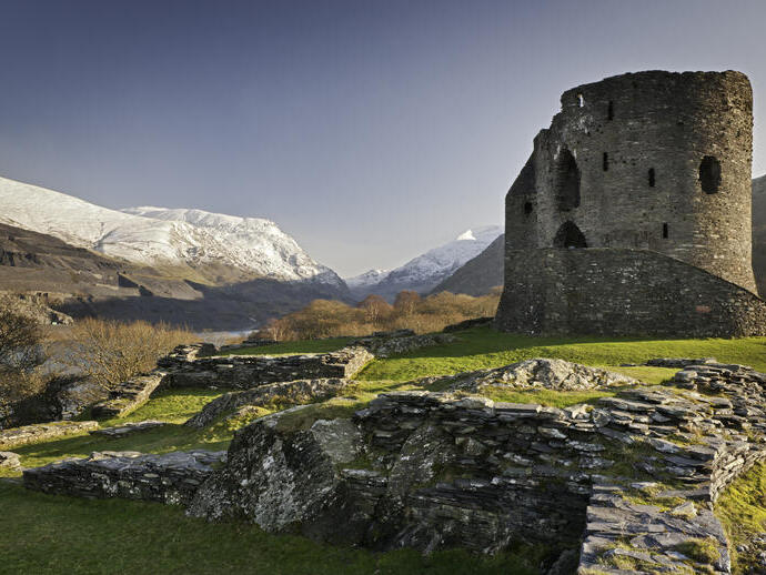 Ruins of a castle in the countryside surrounded by mountains.