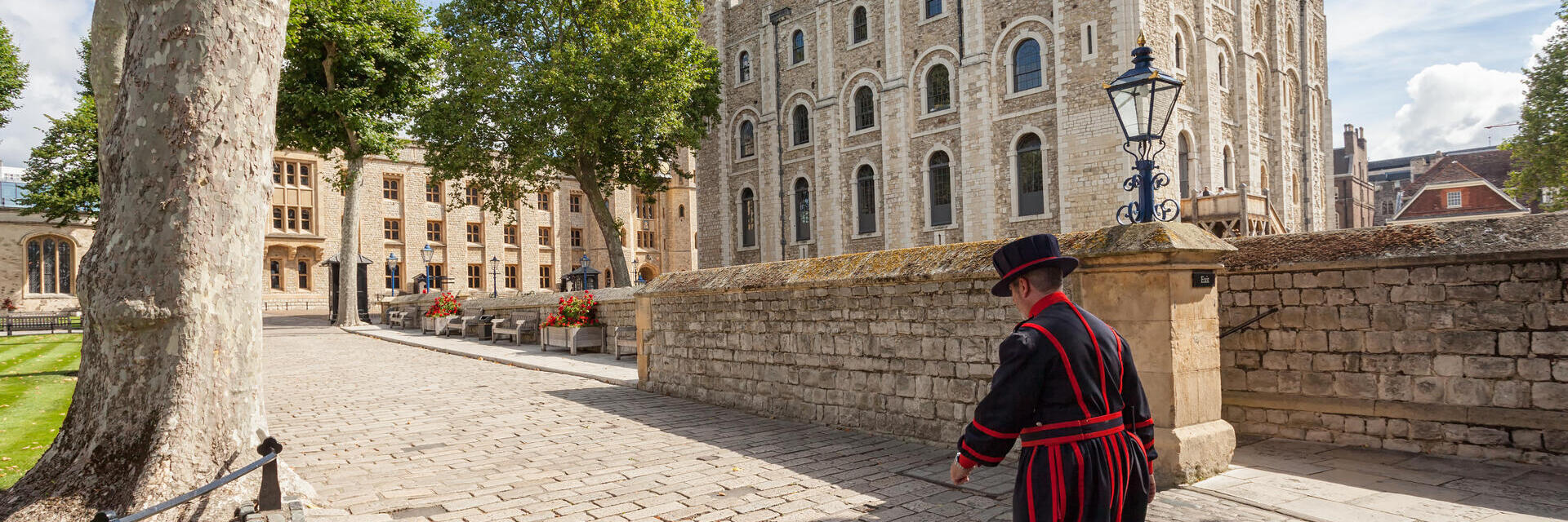 Beefeater che cammina vicino alla Torre di Londra in una giornata di sole