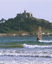 Une personne faisant de la planche à voile au large du château de St Michael's Mount, en Cornouailles