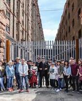 Eine Peaky Blinders-Tourgruppe posiert vor einem Industriegebäude in Liverpool