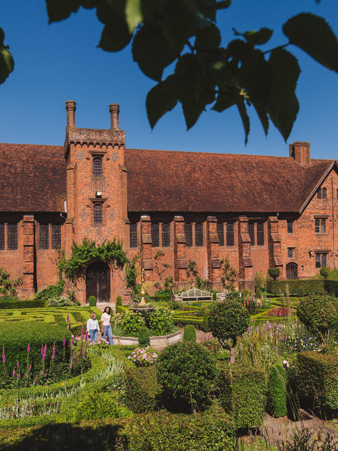 Two women walk through the gardens of a heritage house