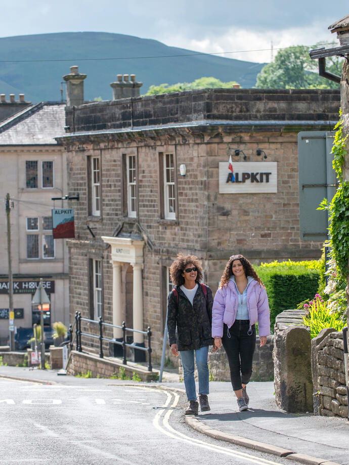 Two women walk through a village set in countryside
