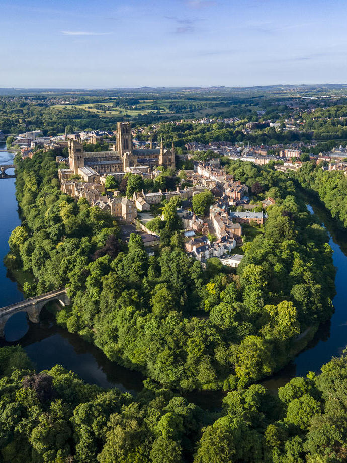 An elevated view of a Cathedral set amongst trees and a river