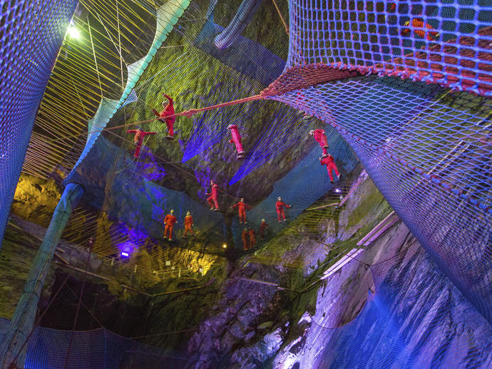 Gruppo di persone che saltano su trampolini sospesi in profonde caverne