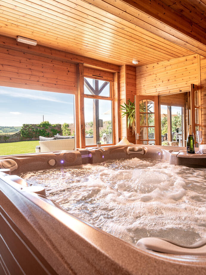 A hot tub view looking out across the lawns at a luxury self catering venue in the countryside.