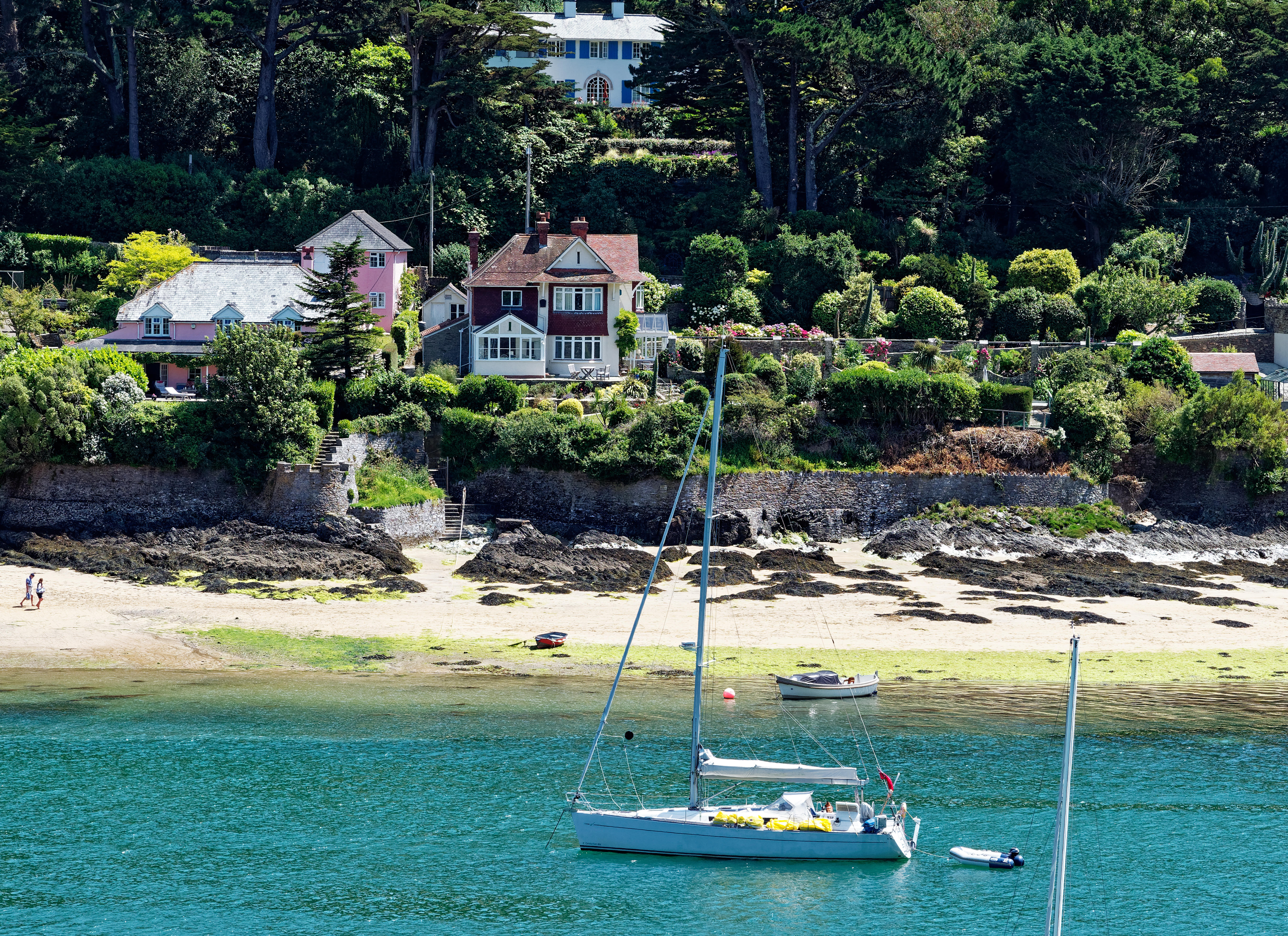A sailing yacht in a quiet harbour with houses in the background