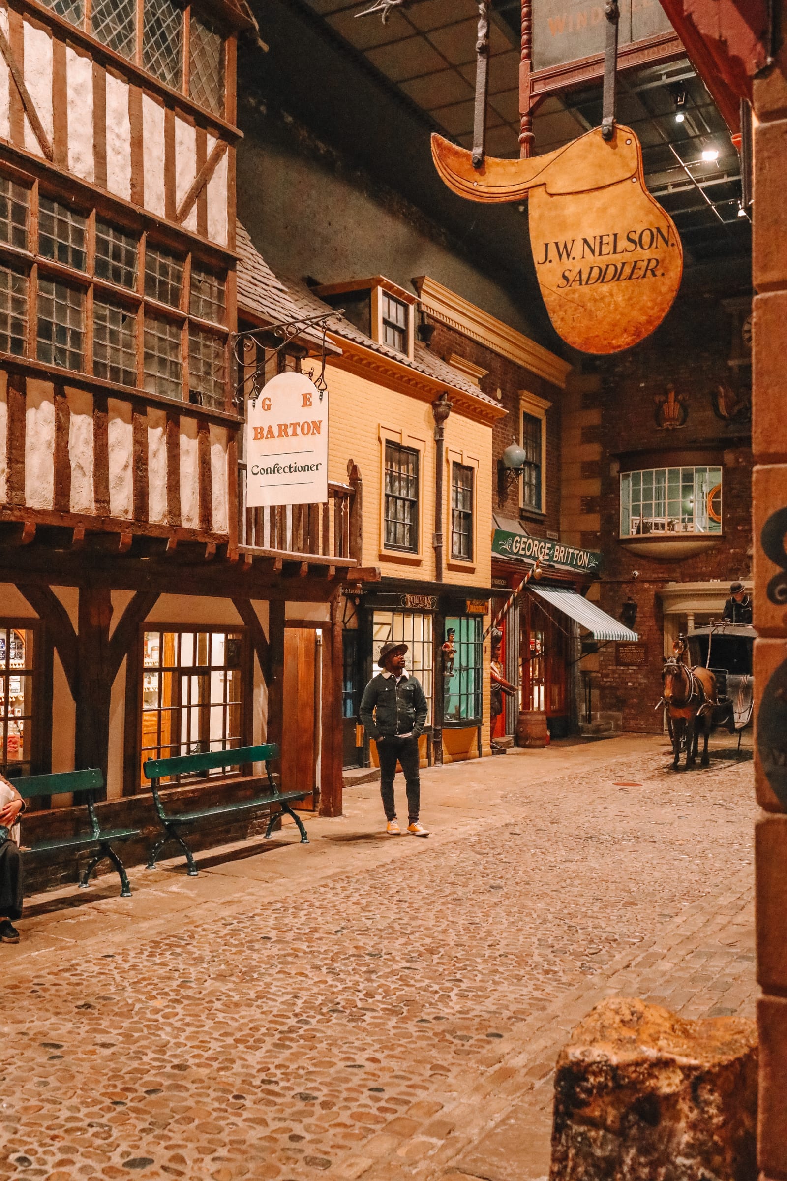 A man standing in an old street, under shop signs