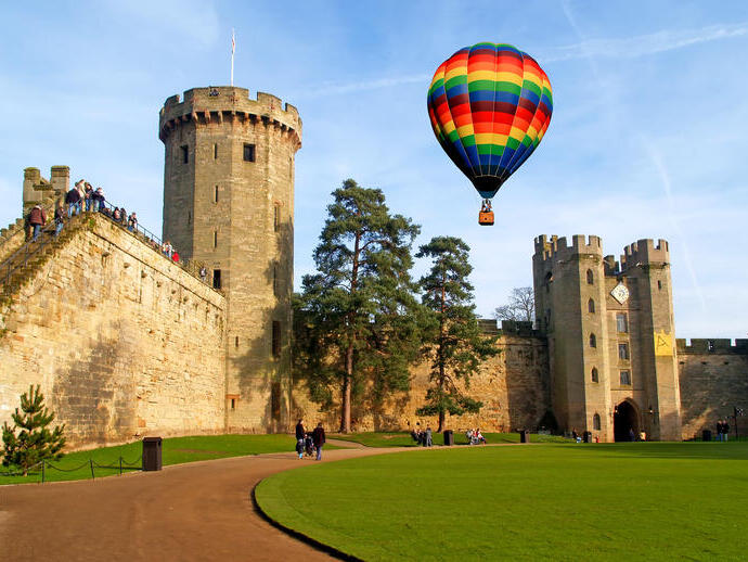 Un globo aerostático flota sobre un castillo y sus cuidados jardines.