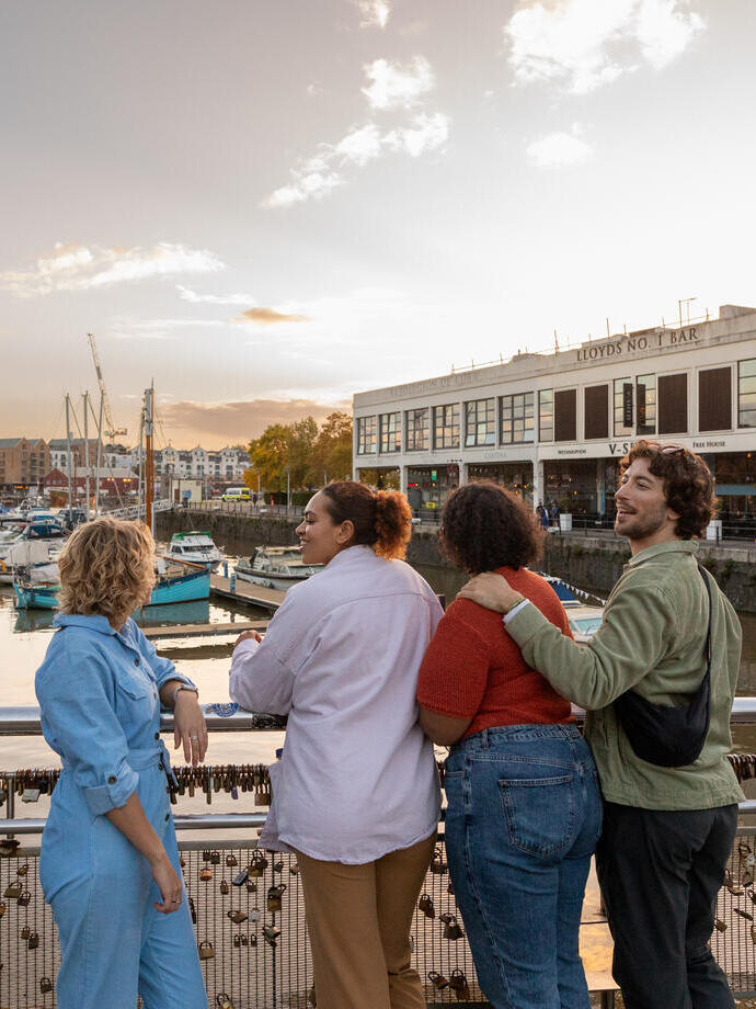 Friends walking over a waterfront bridge.