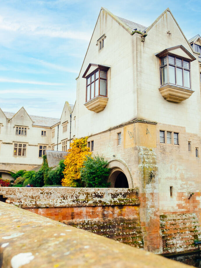 Young couple stood on stone bridge looking at country house