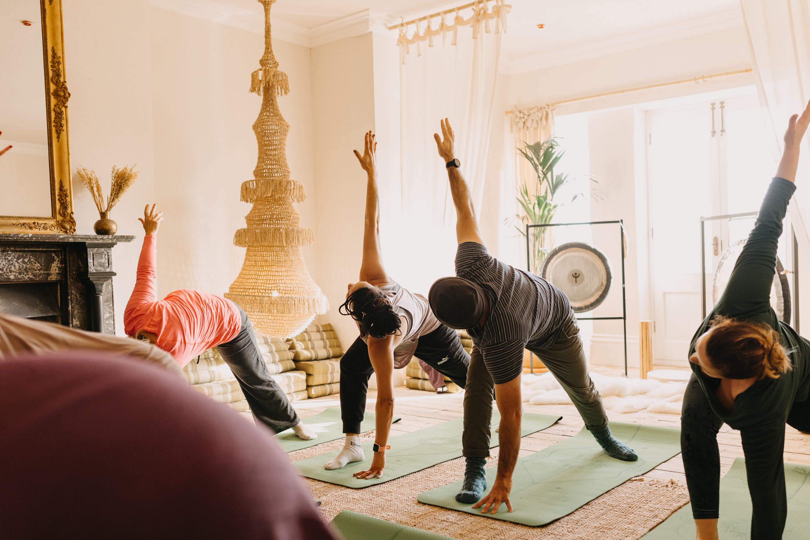 Cuatro personas practican yoga sobre colchonetas durante un retiro de bienestar.