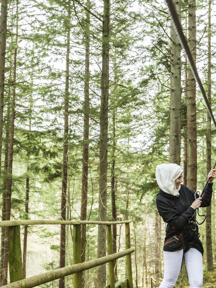 Due donne si preparano a lanciarsi con una teleferica nella pineta