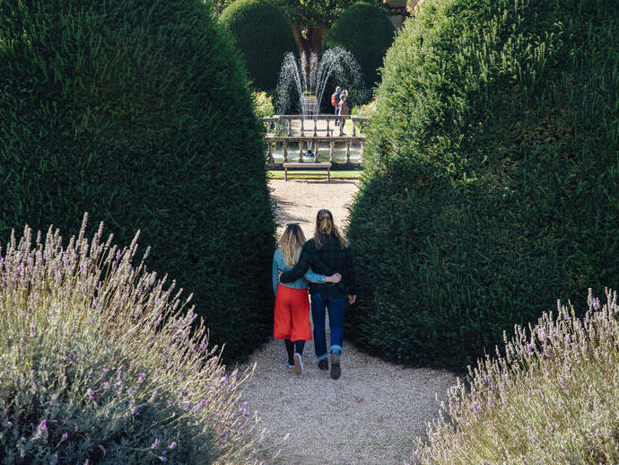 Couple arm in arm walking through formal gardens