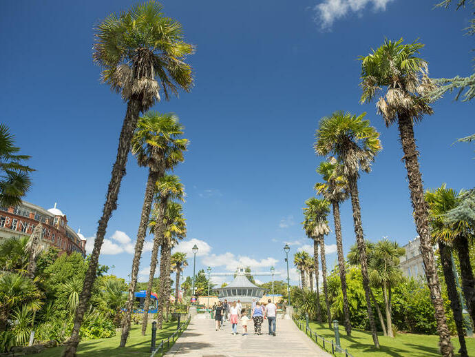 People walking through gardens on a sunny day.