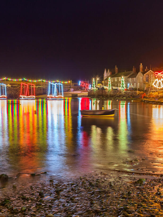 A beautiful evening display of Christmas lights reflecting over a quaint English village & harbour.