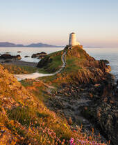 A path leading to a lighthouse on a prominent rocky outcrop by the sea