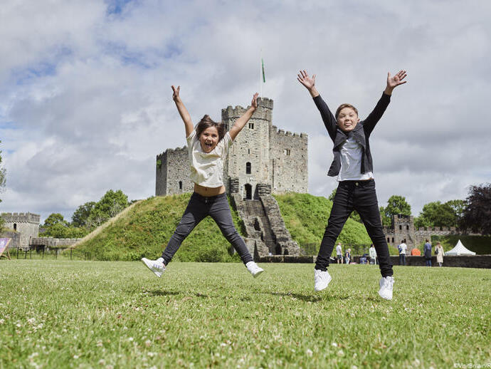 Two children jumping in front of a castle.
