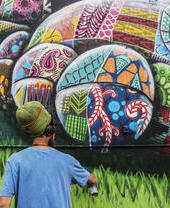 Un artista utilizando pintura en aerosol para diseñar una obra de arte callejero.