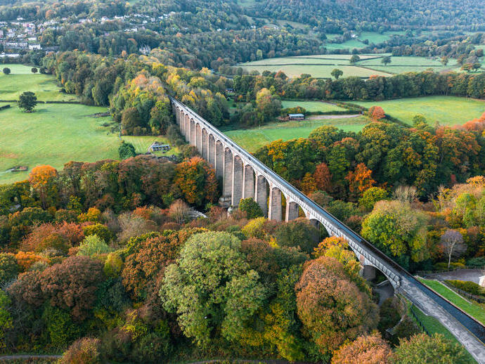 Aerial view of a long viaduct spanning river in an autumnal setting