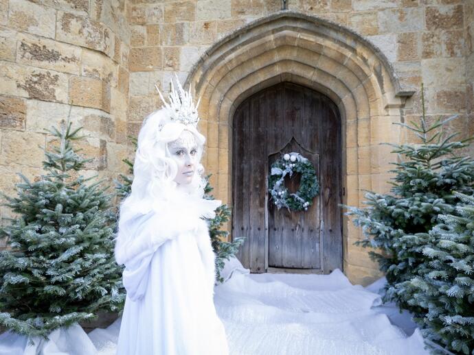 Woman dressed as a white witch outside a castle