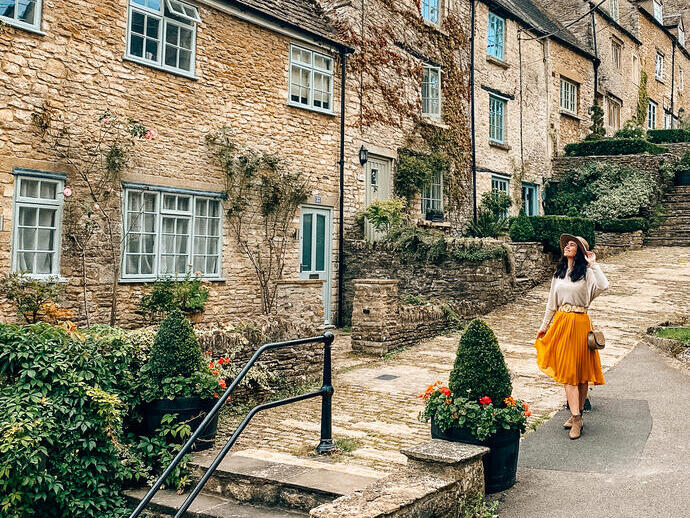A woman in a hat walks down a street in a quaint village