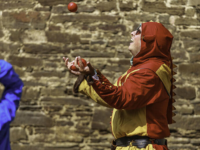 Un jongleur en costume jonglant avec des balles au château de Conwy